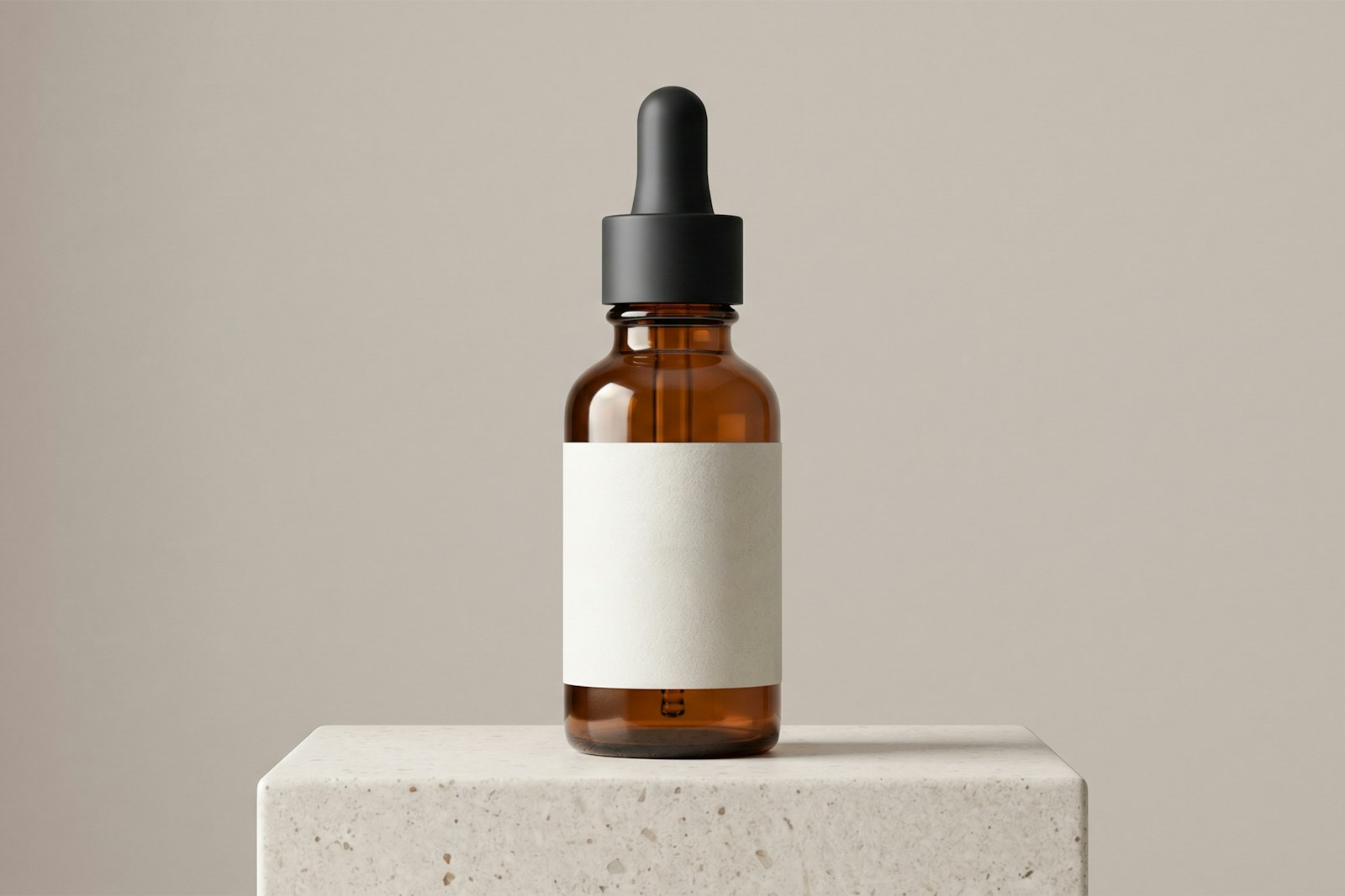 An amber dropper bottle with a blank label on a stone block