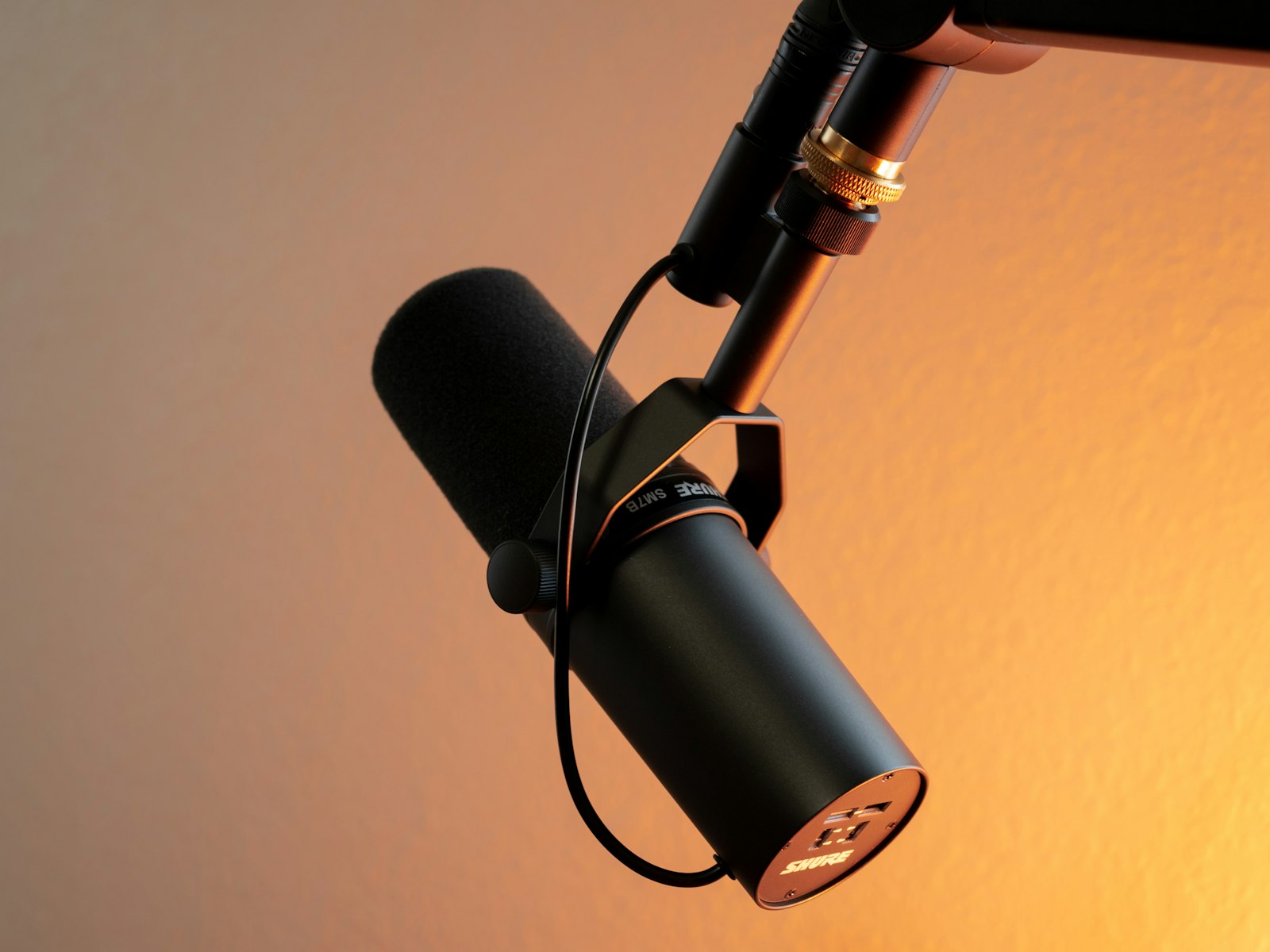 A podcast microphone against a warm wall